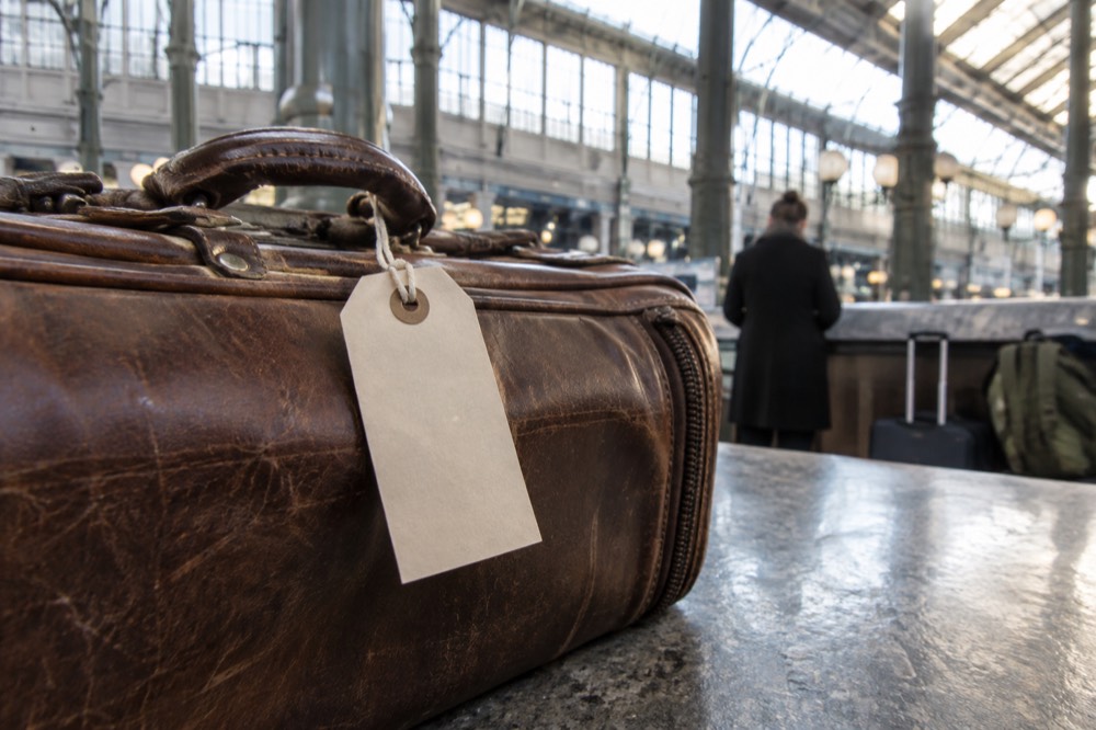 A plain tag looped around a suitcase handle at a storage counter in Paris