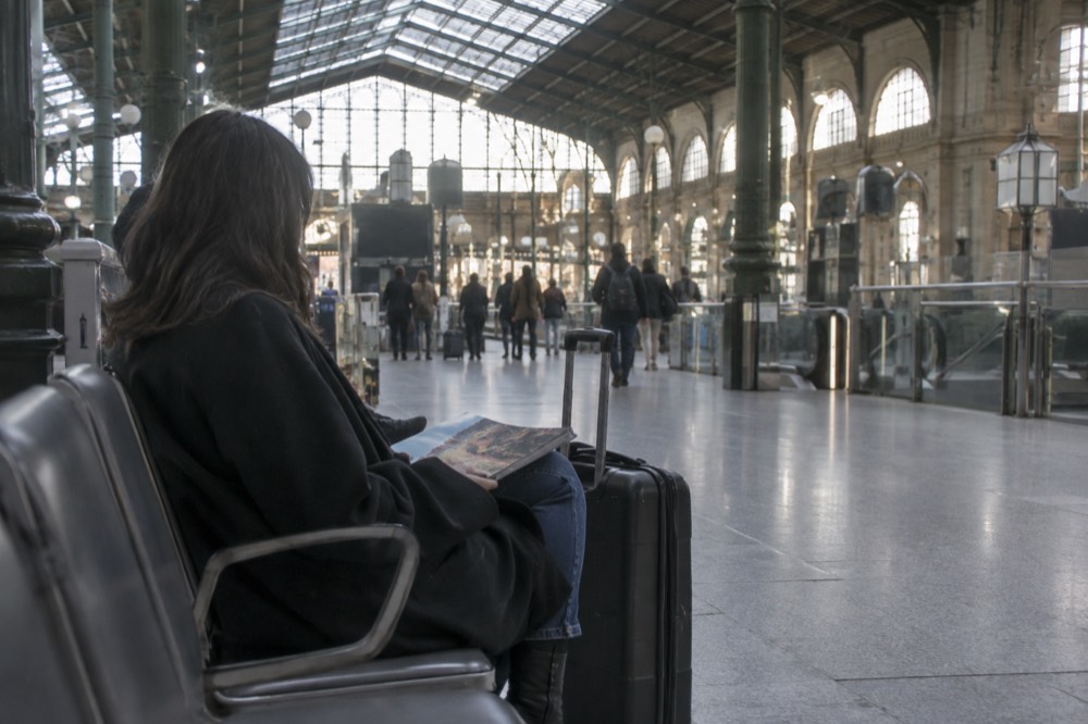 Un voyageur attendant dans un terminal d'aéroport avec une valise à côté d'une rangée de sièges