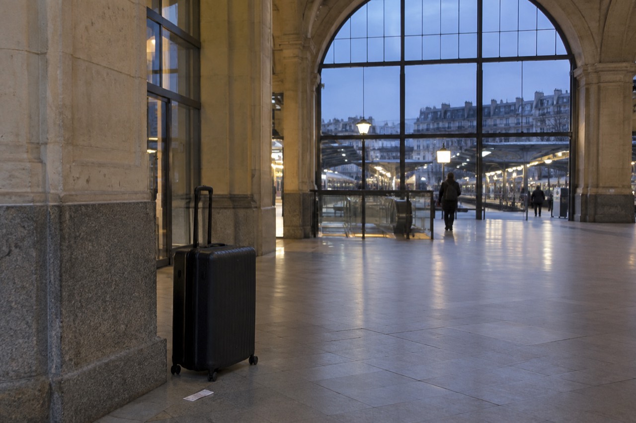 A lone suitcase standing by a window in an empty airport terminal corridor near Paris
