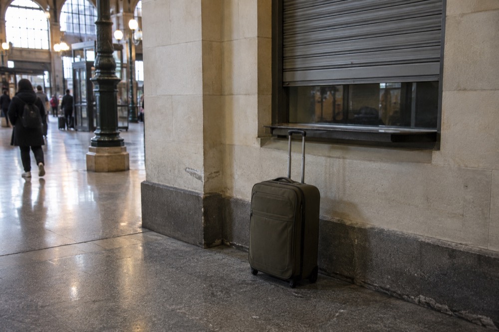 Un guichet fermé dans un couloir de gare parisienne, avec une valise qui attend devant