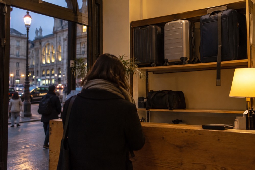 Des valises alignées derrière le comptoir d'un commerce le soir, sous un éclairage chaud