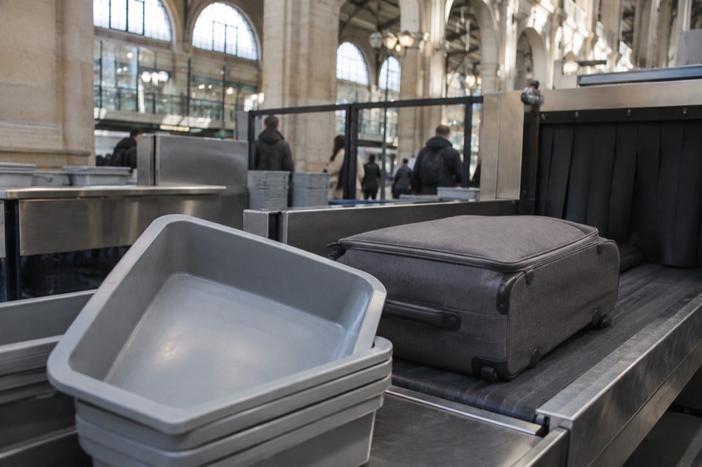 Une valise et des bacs sur un tapis de contrôle de sécurité d'aéroport près de Paris