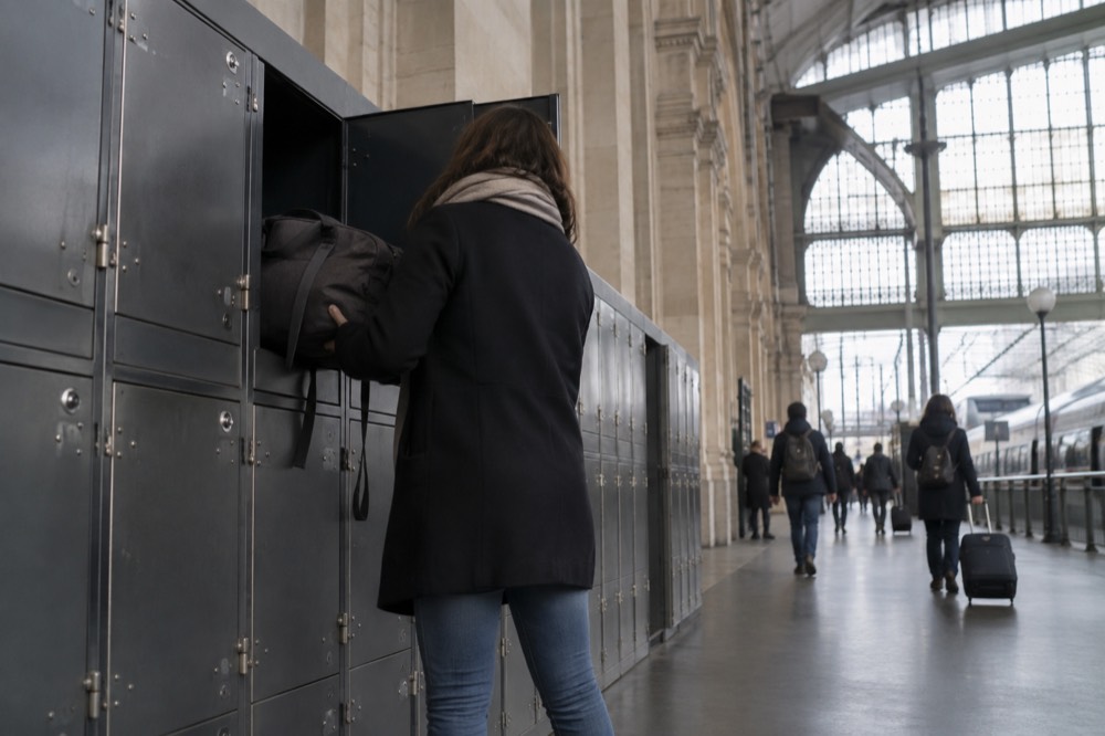 Voyageur plaçant une valise dans un grand casier métallique de gare