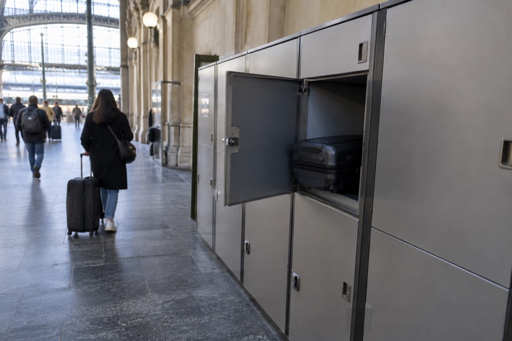 Une rangée de casiers de consigne le long d'un mur dans un couloir de gare bien éclairé