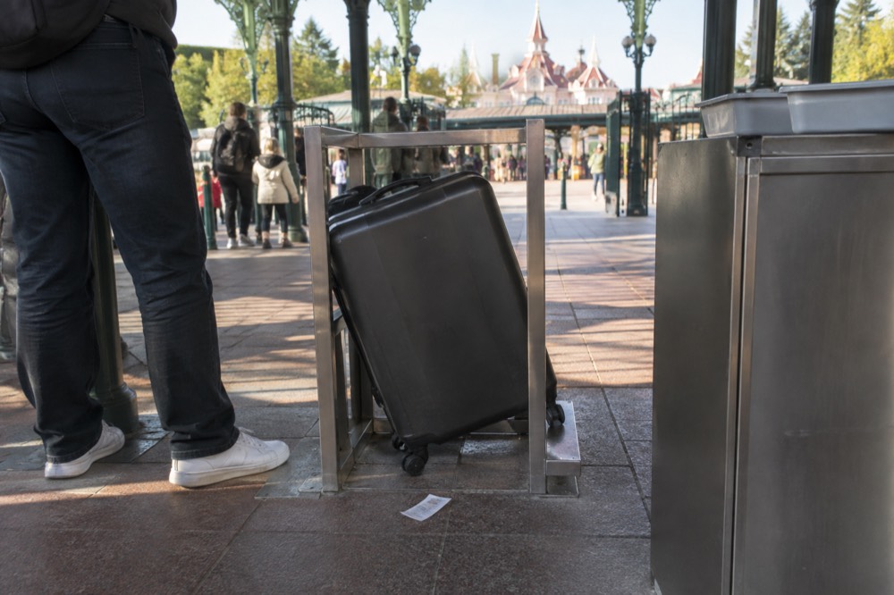 Une entrée de contrôle de sécurité avec un gabarit à bagages à côté du portique dans un parc à thème