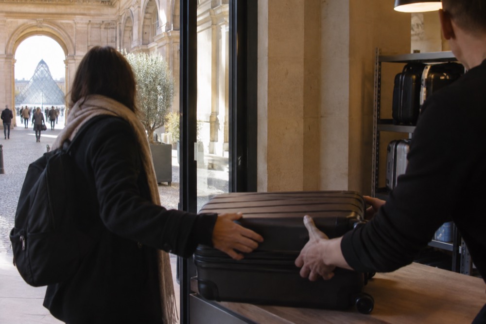 Voyageur remettant une valise par-dessus le comptoir d'une boutique dans un point de consigne urbain