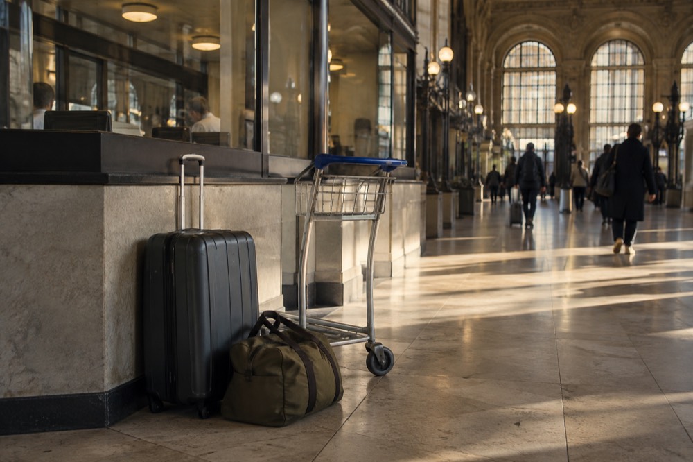 Comptoir de consigne à bagages dans un terminal d'aéroport, avec un guichet tenu par du personnel et des étiquettes à bagage