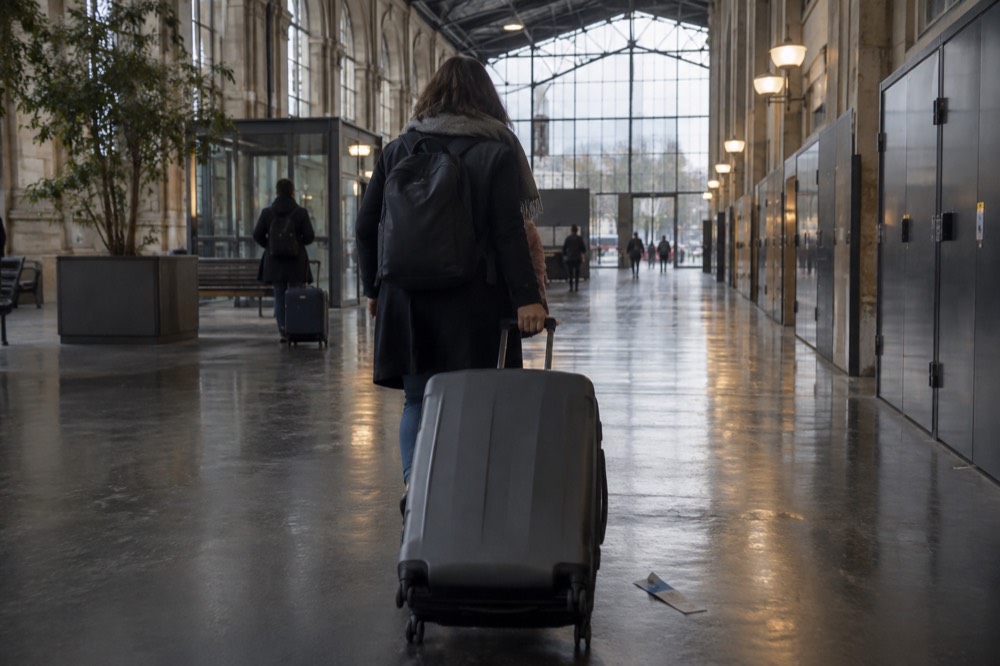 Un voyageur tirant une valise dans un couloir de terminal d'aéroport près de Paris