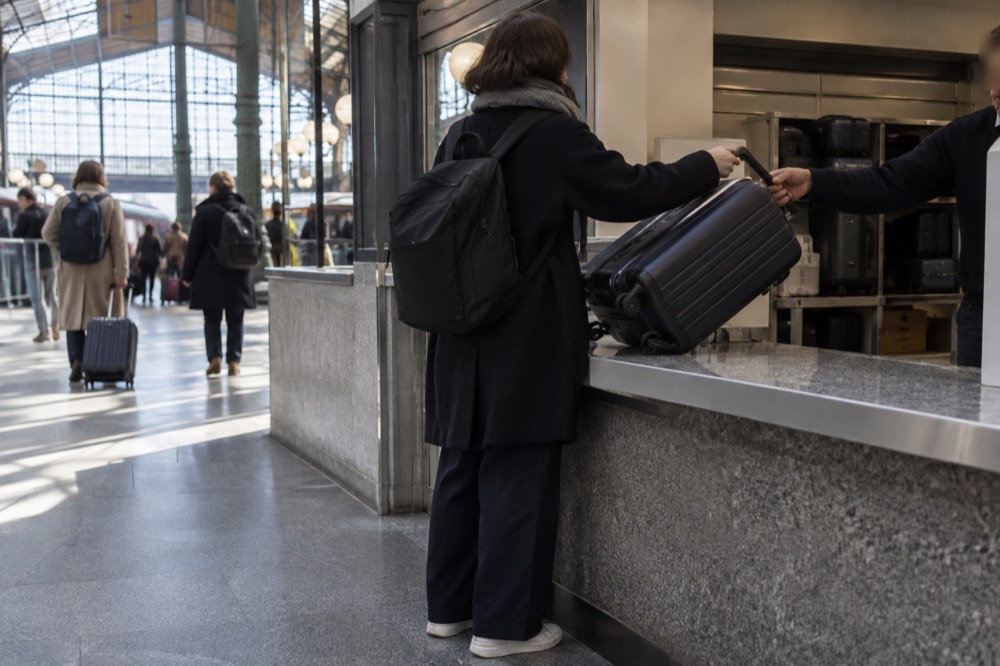 Un guichet de consigne à bagages avec personnel dans une gare, avec une valise en cours de remise