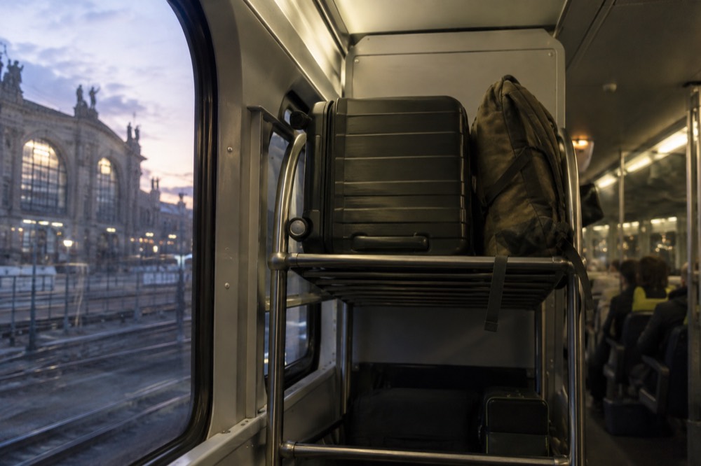 Racks à bagages à l'extrémité d'une voiture de train à grande vitesse, avec une grande valise et un sac à dos rangés