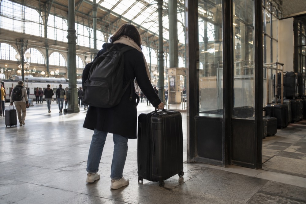 Un voyageur posant une valise dans le hall lumineux d'une gare parisienne
