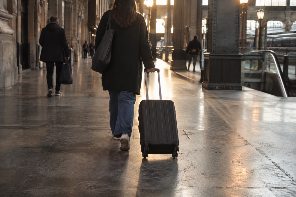 Un couloir de hall d'arrivée d'aéroport avec une valise à roulettes qui avance sur un sol poli