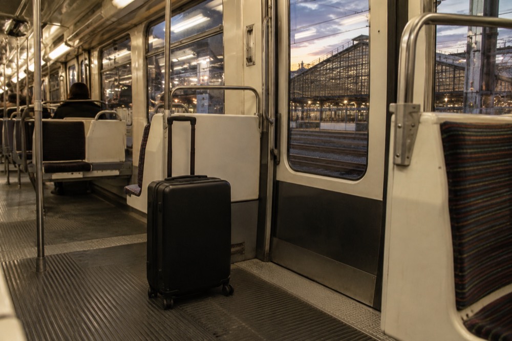 A suitcase standing in the wide vestibule of an empty Paris metro carriage