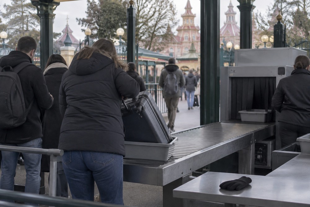 Security checkpoint gates at a theme park entrance with bag screening tables