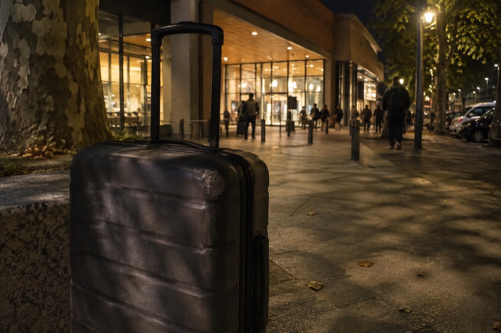 Une valise devant une devanture parisienne éclairée, la nuit