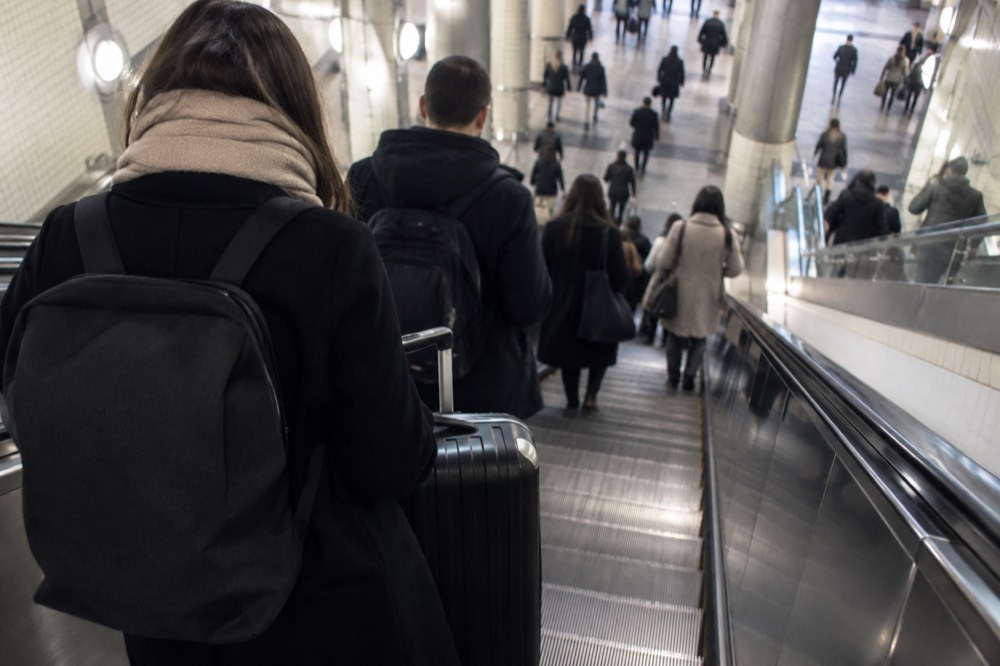 A suitcase held close on a crowded Paris Metro platform at rush hour