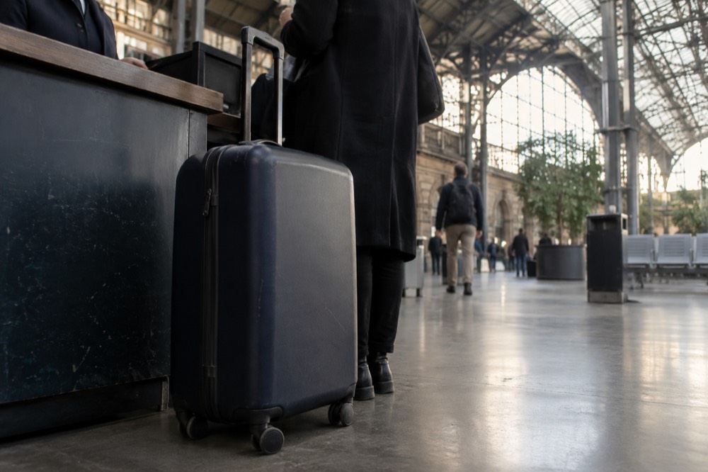Une valise posée au sol devant un comptoir de service avec personnel dans un terminal d'aéroport près de Paris
