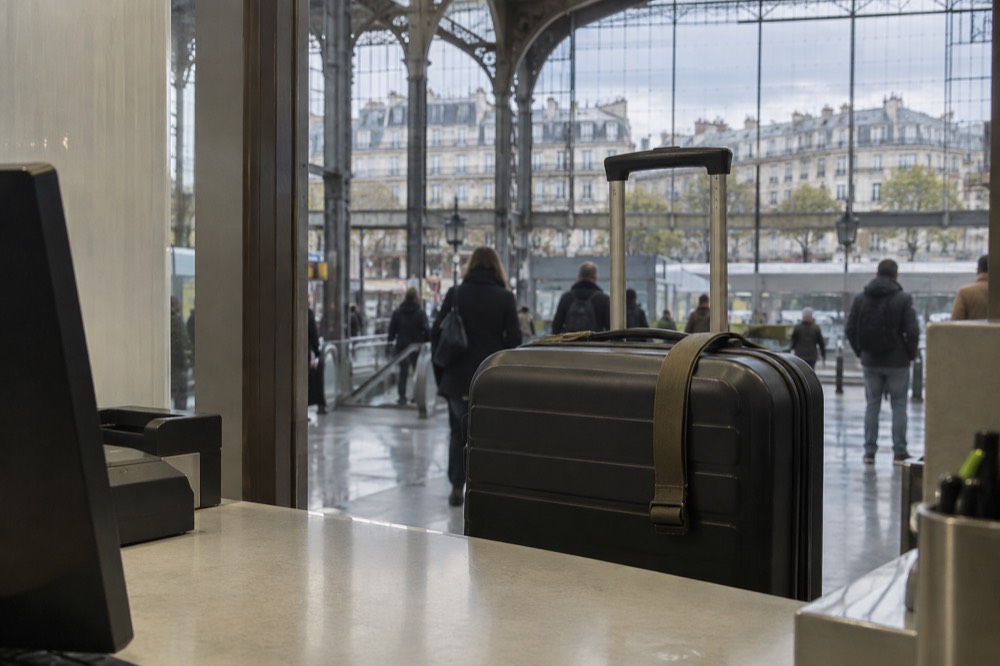 Une valise à roulettes posée à un comptoir de service dans un hall d'arrivées d'aéroport près de Paris