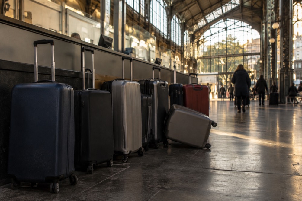 Une rangée de valises à roulettes posées près d'un comptoir dans une zone de service d'aéroport