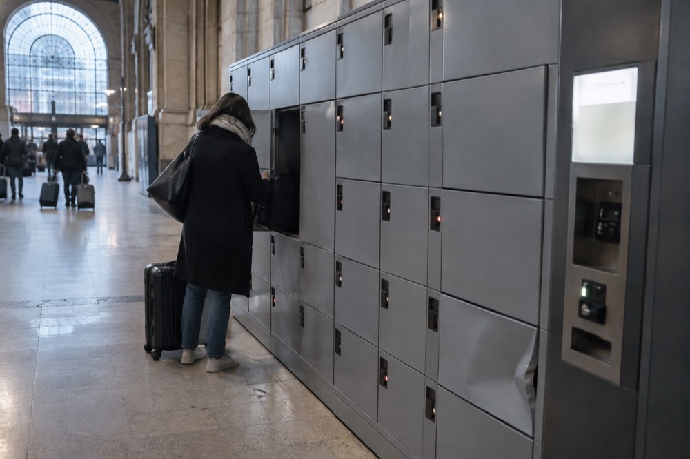 Une rangée de casiers à bagages en libre-service dans un couloir de gare avec un terminal de paiement