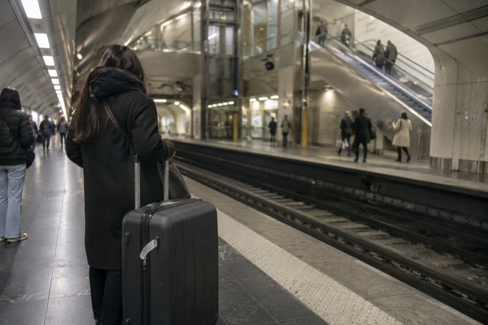 Quai de métro avec un voyageur debout à côté d'une grande valise attendant une rame