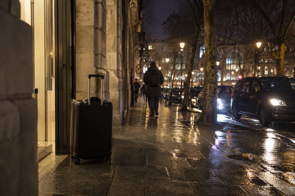 Une valise devant l'entrée éclairée d'une boutique à Paris, la nuit