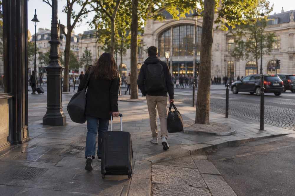 Des voyageurs entrant dans un hôtel parisien avec leurs bagages après une journée de visites