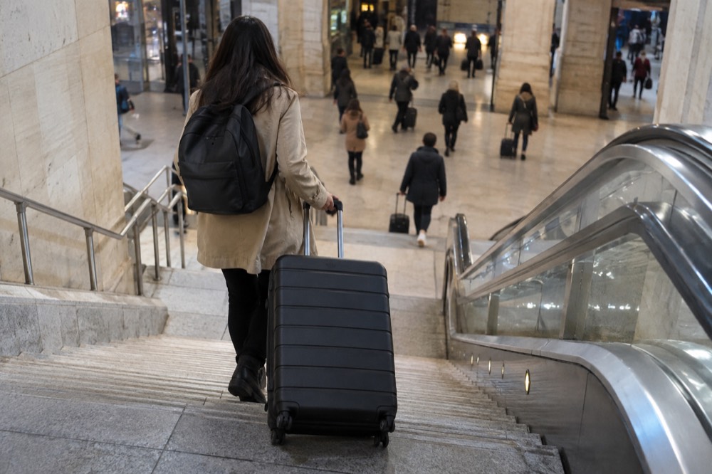A traveller wheeling a case down to the lower level of Gare du Nord in Paris
