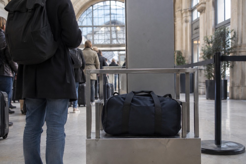 Entrée d'un contrôle de sécurité dans un monument français avec un gabarit à bagages à côté du portique