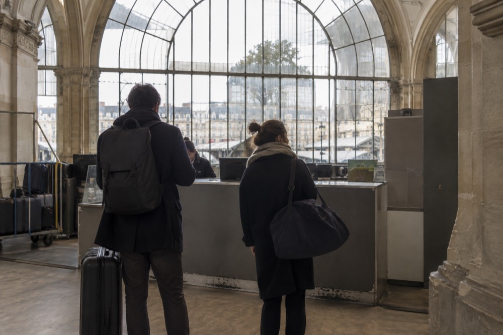 Un guichet de consigne avec personnel dans une gare parisienne, avec une file de deux voyageurs.